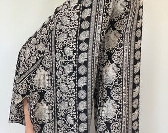 May include: Black and white palazzo pants with an elephant print. The pants have a wide leg and a high waist. The fabric is soft and flowy.