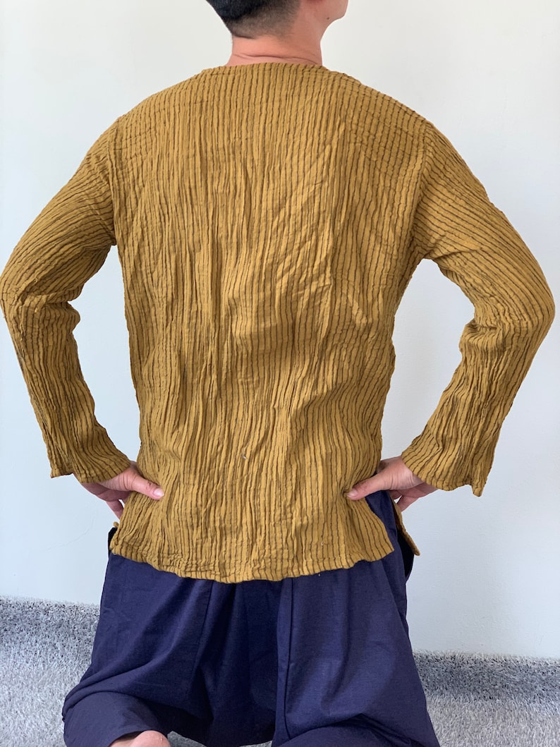 May include: A long-sleeved shirt in a mustard yellow colour with a textured, ribbed fabric. The shirt has a v-neck and a relaxed fit.