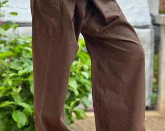May include: Brown wide-leg pants with a wrap-around waistband and a single pocket on the left side.