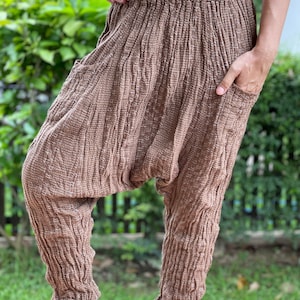 Puede incluir: Pantalón de algodón marrón con un corte holgado y cintura elástica. El pantalón tiene una textura arrugada.