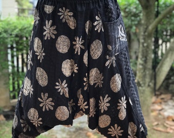 May include: Black cotton pants with a white floral and circle print. The pants have a wide leg and a drawstring waist.