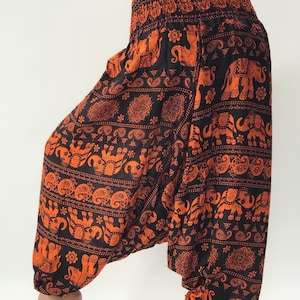 Könnte beinhalten: Schwarze Haremshosen mit einem orangefarbenen Elefanten- und Paisley-Druck.