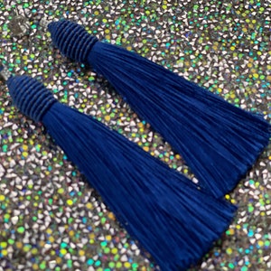 May include: A pair of long, blue tassel earrings. The tassels are made of thin, silky fabric and are attached to a small, silver-toned hook.