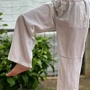 May include: White cotton pants with a drawstring waist. The pants are loose fitting and flowy.