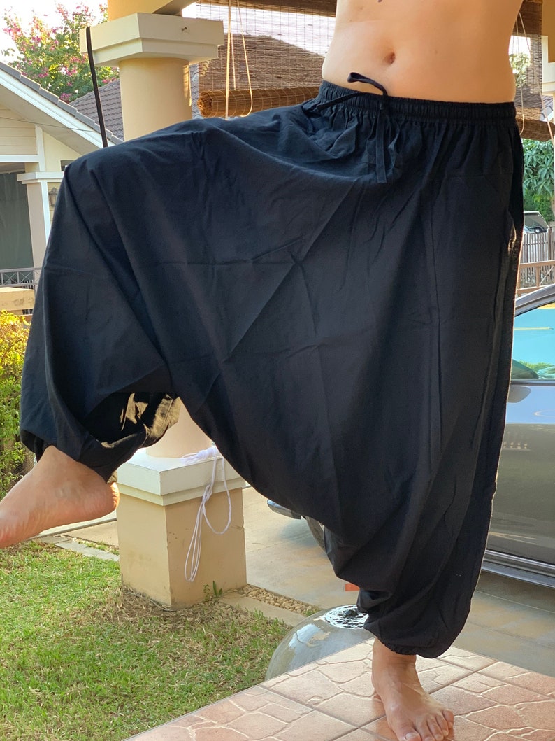 May include: Black cotton pants with a drawstring waist. The pants are loose fitting and have a wide leg.