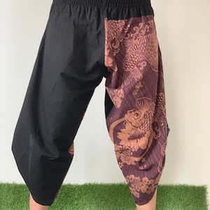 May include: Black and brown patterned pants with an elastic waistband. The pants have a unique design with a fish pattern on one leg.