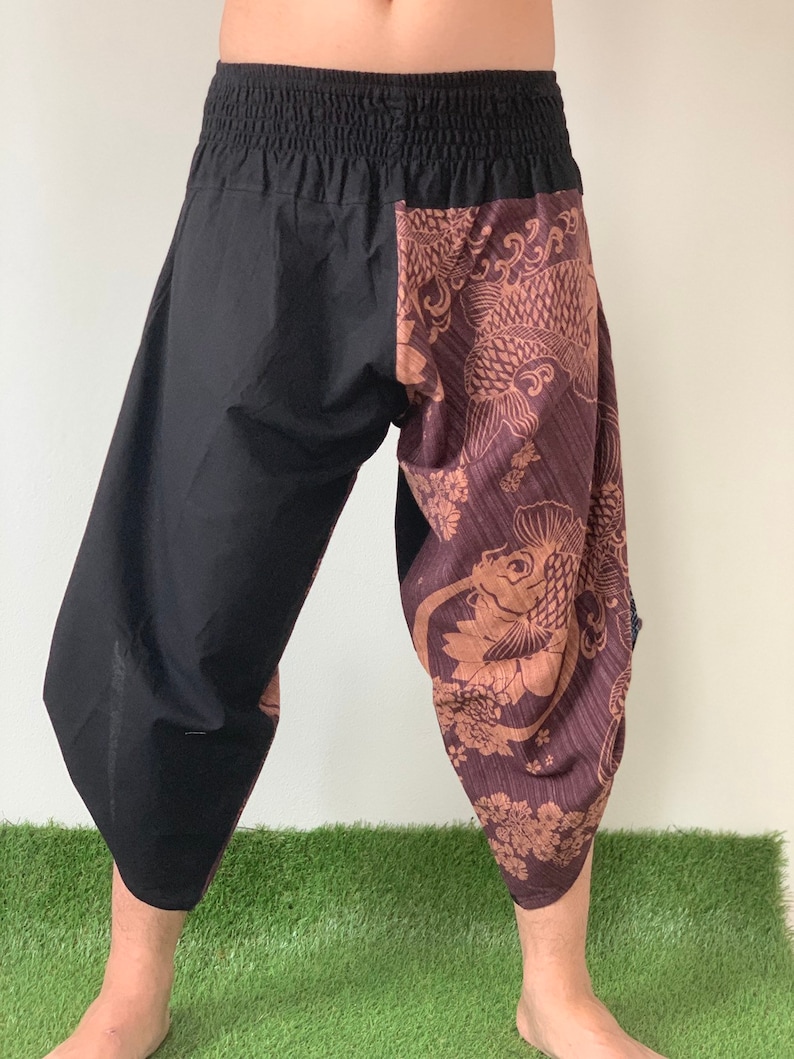 May include: Black and brown patterned pants with an elastic waistband. The pants have a unique design with a fish pattern on one leg.