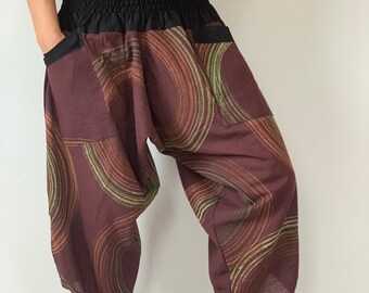 May include: Brown pants with a black elastic waistband and a green and brown abstract pattern. The pants have a large pocket on the left side.