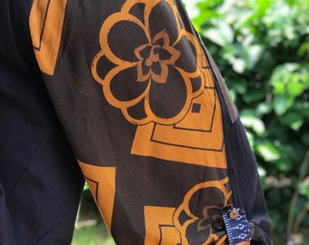 May include: Black trousers with a brown and gold floral print. The trousers have a drawstring waistband and a button fastening.