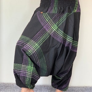 May include: Black harem pants with a green and purple plaid pattern. The pants have an elastic waistband and a drawstring.
