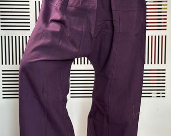 Può includere: Pantaloni larghi viola con una vestibilità ampia e fluida. I pantaloni hanno una cintura con coulisse e uno stile rilassato e comodo.