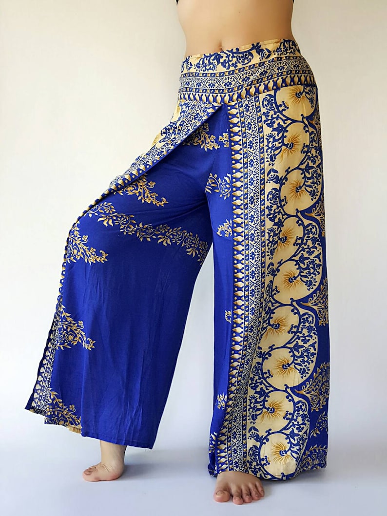 May include: Wide-leg trousers in blue with a gold and white floral print. The trousers have a wrap-around style and a high waist.