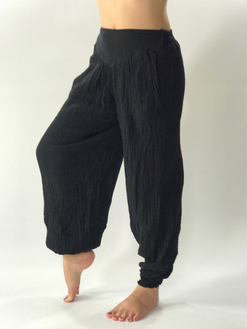 May include: Black, loose-fitting pants with a wide, gathered waistband. The pants are made of a soft, textured fabric and have a flowing, relaxed fit.