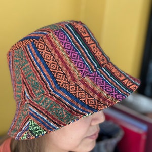 Puede incluir: Un sombrero de cubo colorido con un patrón geométrico en tonos de naranja, rosa, azul, verde y negro.