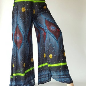 May include: Wide-leg pants with a black background and a blue, red, and gold patterned design. The pants have a green and black waistband with a multi-colored trim.