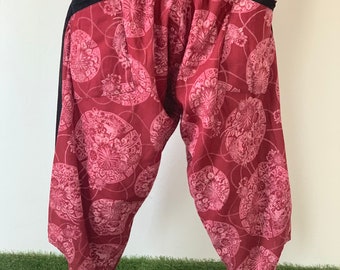 May include: Red and black patterned pants with an elastic waistband. The pants have a loose, flowing fit and are made of a lightweight fabric.