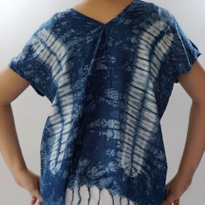 May include: A blue and white tie-dye cotton top with a V-neck and short sleeves. The top has a fringed hem.