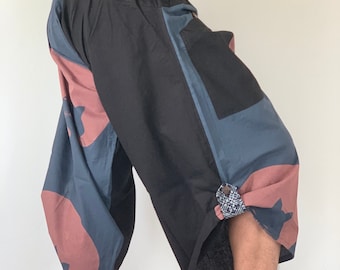 May include: Black and blue patterned pants with a drawstring waist and a pocket on the side. The pants have a loose, flowing fit.