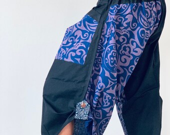 May include: Black and blue patterned pants with a wide leg and elastic waistband. The pants have a unique design with a mix of geometric and floral patterns.