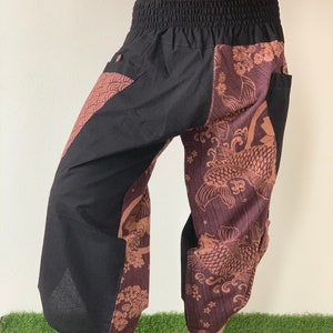 May include: Black pants with a brown and black patterned design featuring koi fish and floral motifs. The pants have an elastic waistband and side pockets.