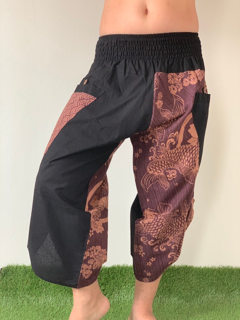 May include: Black pants with a brown and black patterned design featuring koi fish and floral motifs. The pants have an elastic waistband and side pockets.