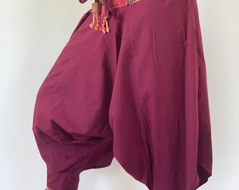 May include: Burgundy harem pants with a colorful patterned waistband and matching trim at the ankles. The pants have a drawstring closure and a loose, flowing fit.