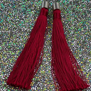 May include: A pair of long, burgundy tassel earrings with silver metal tops.