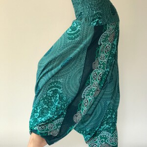 May include: Teal blue printed trousers with a paisley design. The trousers have a wide leg and a gathered waist.
