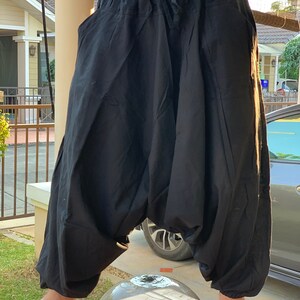 May include: Black cotton pants with a drawstring waist and a loose, baggy fit. The pants have a wide leg and a comfortable, relaxed style.