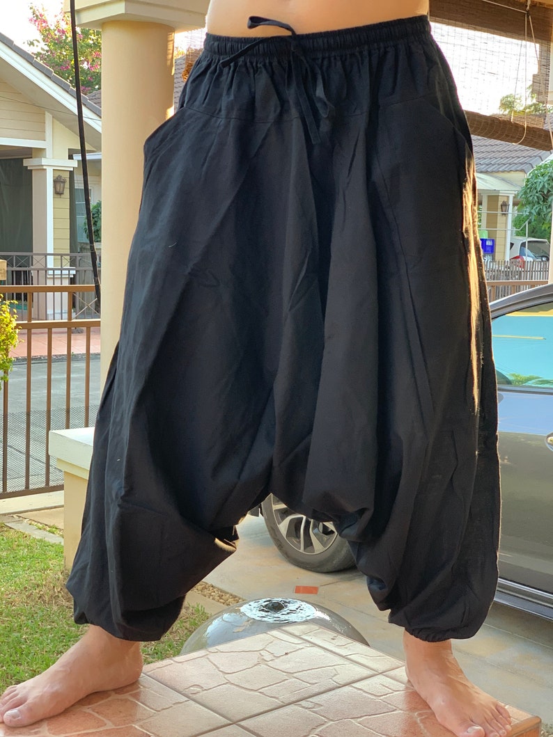 May include: Black cotton pants with a drawstring waist and a loose, baggy fit. The pants have a wide leg and a comfortable, relaxed style.