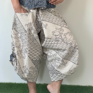 May include: White pants with a black and white wave pattern. The pants have a blue and white patterned waistband.