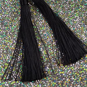 May include: A pair of long black tassel earrings. The tassels are made of thin black threads and are about 4 inches long.