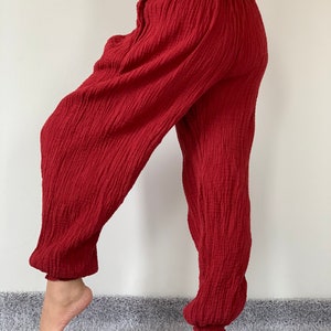 May include: Red cotton pants with a wide leg and elastic waistband. The pants are made of a soft, comfortable fabric and have a relaxed fit.
