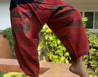 May include: Red, green, and black patterned pants with a black elastic waistband. The pants are loose-fitting and have a wide leg.