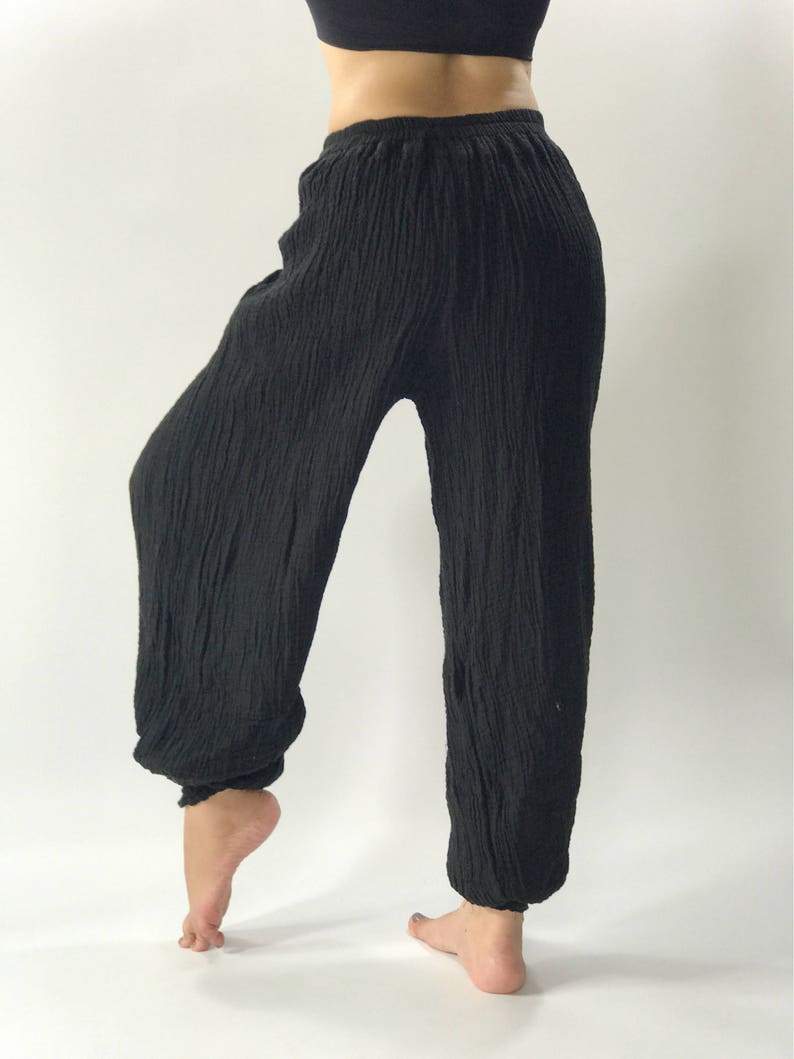 May include: Black, loose-fitting pants with a gathered elastic waistband. The pants are made of a soft, crinkled fabric.