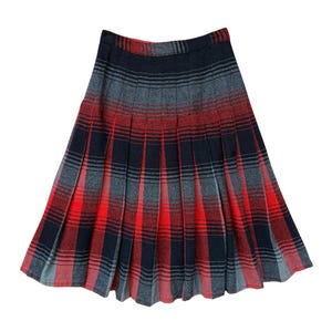 May include: A knee-length pleated skirt featuring a tartan pattern in shades of charcoal grey, black, and vibrant red. The garment has a structured waistband and vertical pleats that extend from the waist to the hem, creating a flared silhouette.