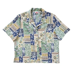 Peut inclure: Une chemise à manches courtes boutonnée avec un motif patchwork composé de fleurs et de formes géométriques dans des tons vert sauge, bleu marine et beige. Elle présente un col à revers et une étiquette au col indiquant alia petite.