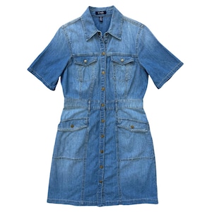May include: A light blue denim shirt dress featuring short sleeves, a classic collar, and a full-length front button placket with metallic buttons. The garment includes two chest pockets with flaps and two hip pockets, all with button closures.