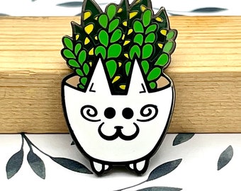 May include: White ceramic planter shaped like a cat with green succulent plants growing out of the top.