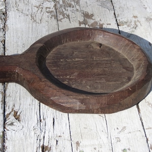 May include: A dark brown wooden serving tray with a rounded handle. The tray has a deep, circular well in the center.