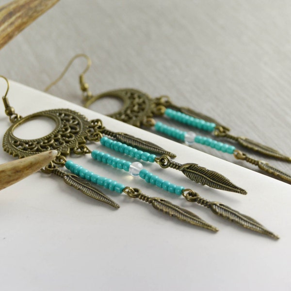 Boucles d'oreille chandelier style attrape-reves en perles de rocaille turquoises / vertes et plumes bronze