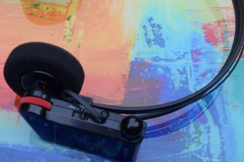 Pode incluir: Um tocador de cassetes Sony Walkman preto e vermelho com uma faixa de cabe&ccedil;a preta e um fone de ouvido preto. O tocador tem um bot&atilde;o prateado e o texto "AM/FM" &eacute; vis&iacute;vel no lado.