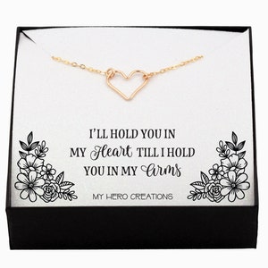 May include: A gold necklace with a heart pendant in a black box. The box has a white background with the text "I'LL HOLD YOU IN MY Heart TILL I HOLD YOU IN MY Arms MY HERO CREATIONS".