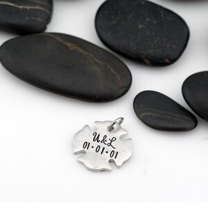 May include: Silver firefighter's helmet charm with the inscription "U&L 01.01.01" on a white background.