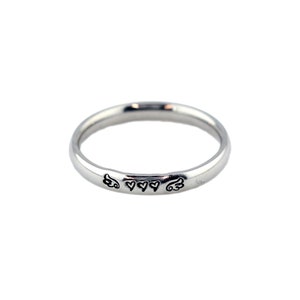 May include: A silver band ring with a design of two wings and three hearts on the band.
