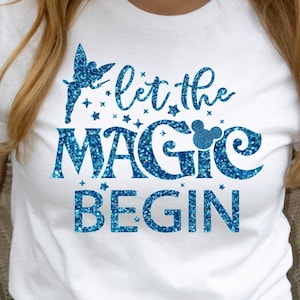 May include: White t-shirt with blue glitter lettering that says "Let the Magic Begin" with a Tinkerbell silhouette and a Mickey Mouse head.