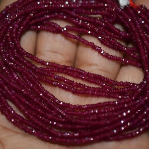 May include: A strand of deep red ruby beads, faceted and strung together. The beads are small and uniform in size, creating a delicate and elegant look.