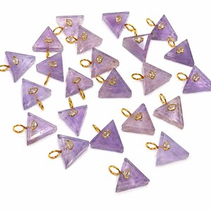 May include: A collection of triangular-shaped amethyst pendants, each featuring a translucent light purple stone set with a small gold-toned metal bail and a tiny clear marquise-cut accent stone attached to the top corner of the triangle.