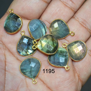 Puede incluir: Un grupo de ocho colgantes de piedra de labradorita en forma de lágrima con anillas de salto doradas. Las piedras son una mezcla de colores verde, azul y dorado. El número 1195 está impreso en la imagen.