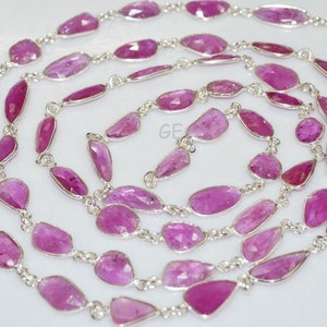 Könnte beinhalten: Eine Kette aus rosafarbenen Edelsteinperlen, die auf einer silbernen Kette aufgefädelt sind. Die Perlen sind facettiert und haben eine Tropfenform. Die Kette besteht aus kleinen, filigranen Gliedern.